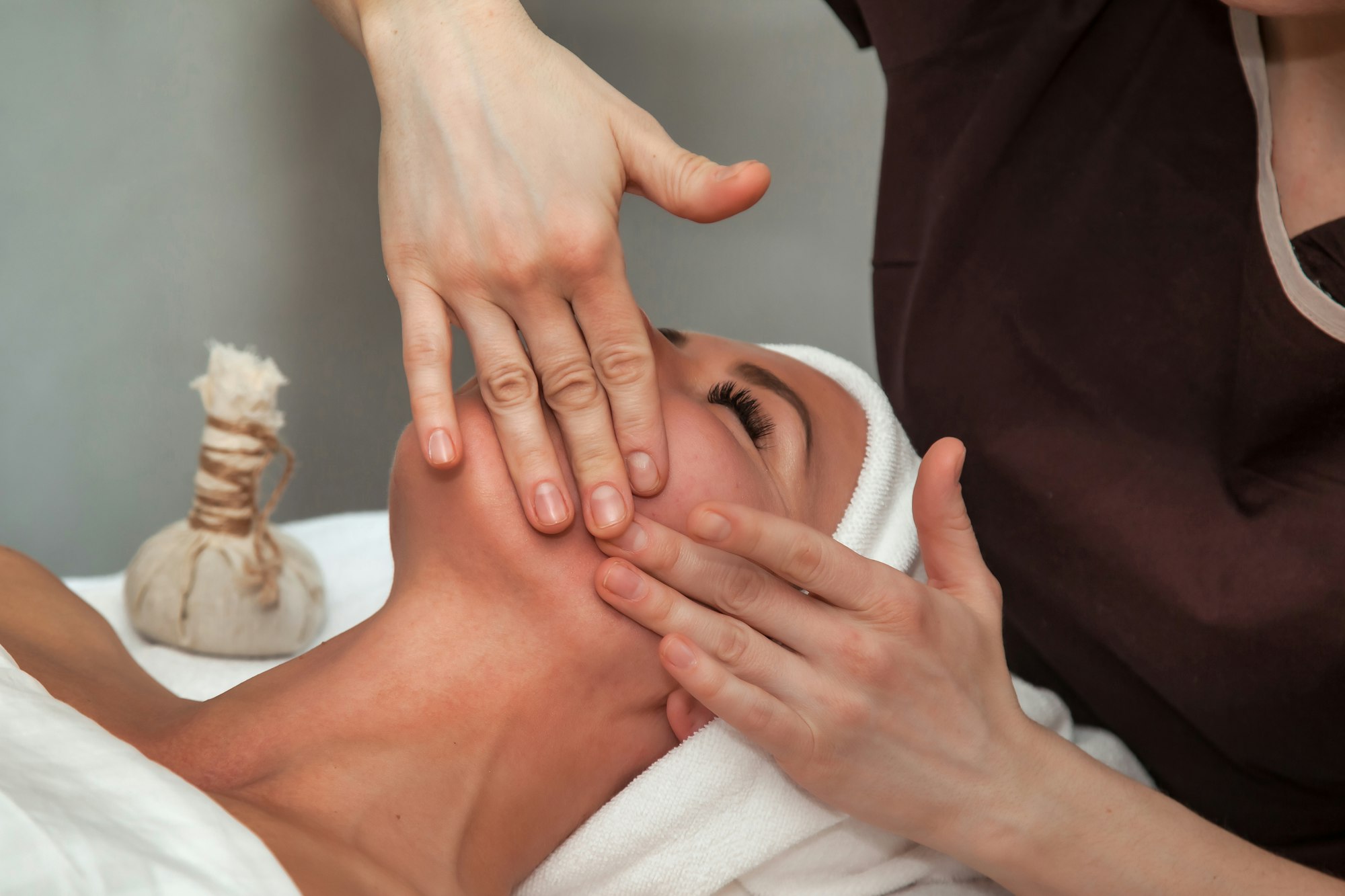 Massaging therapist makes facial therapy mass for female. Face massage woman in SPA salon